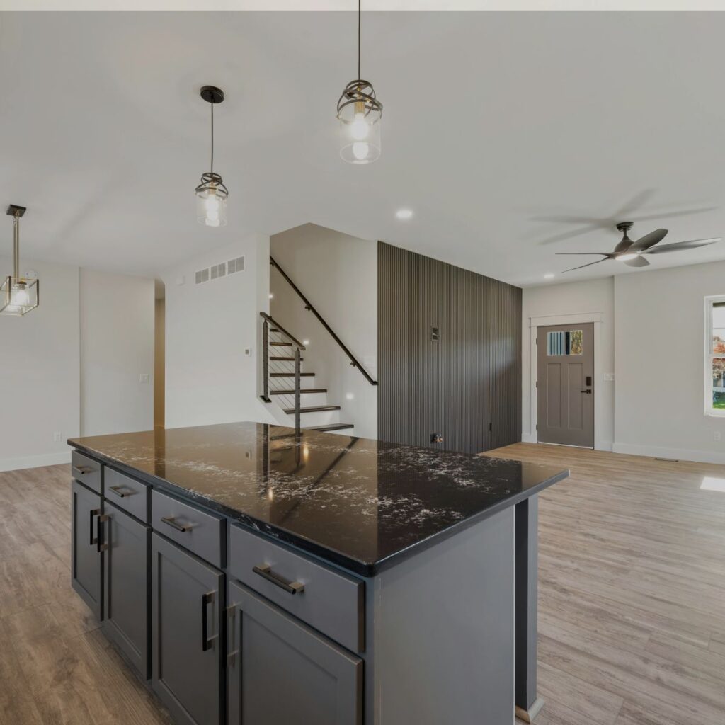 Modern open-plan kitchen featuring wood-look epoxy flooring in Lakewood Ranch, FL, with a glossy black island countertop.