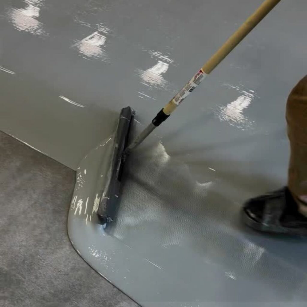 Professional installation of smooth gray Epoxy Flooring North Port FL using a floor roller.